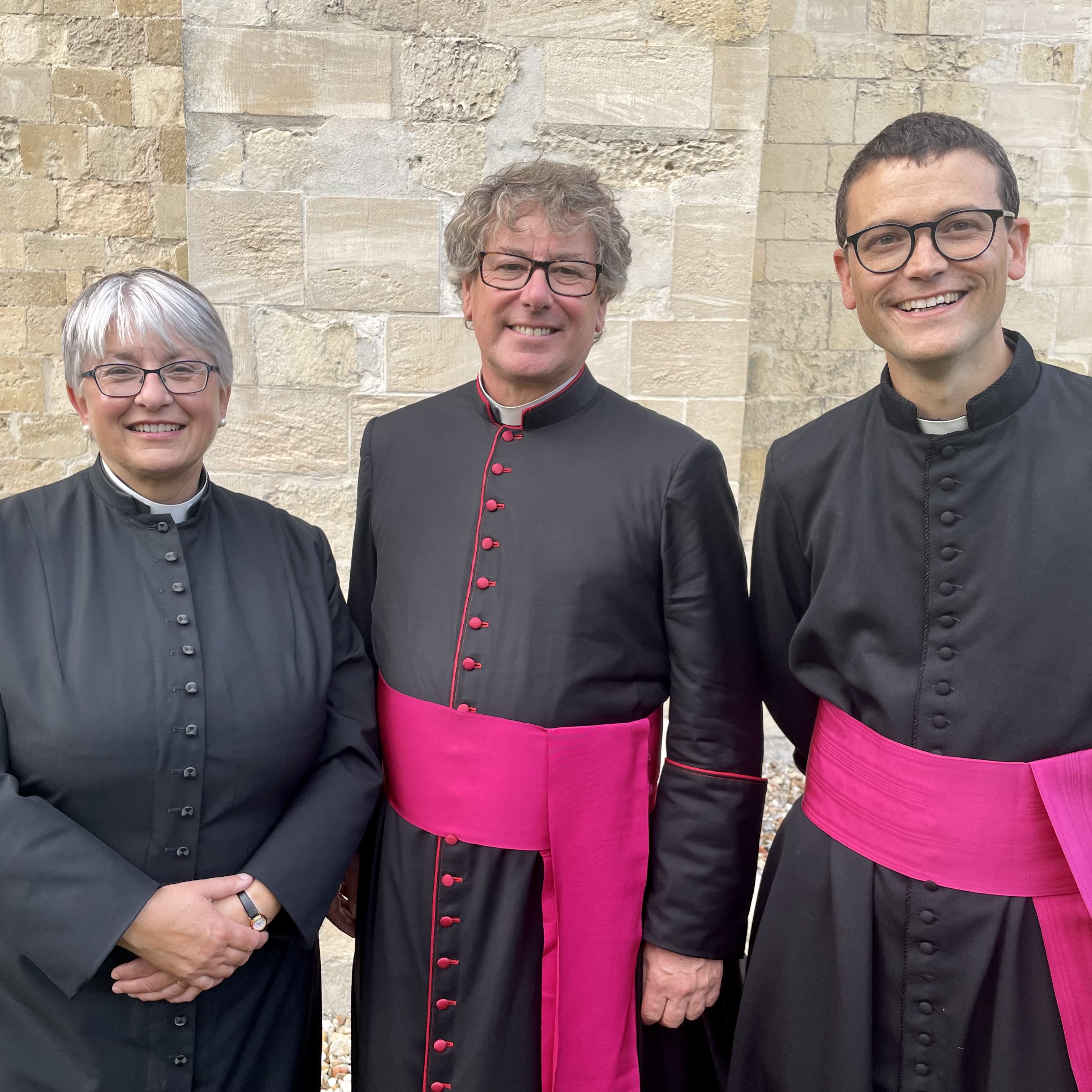 The Dean of Chichester stands alongside two new Canons, wearing black