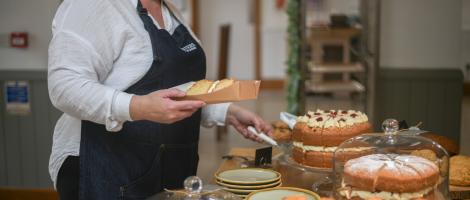 A cafe worker cuts a sponge cake