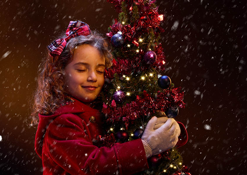 Hey Christmas tree promotional image of a girl hugging a christmas tree