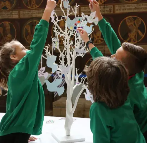 School children writing messages of peace and hanging them on a tree of hope