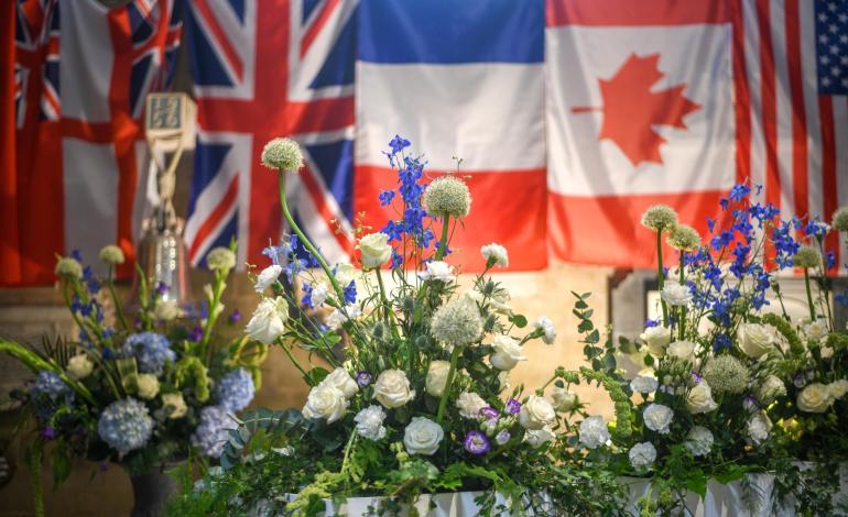 Blue and white flowers in front of a UK, Canada, French & American flag