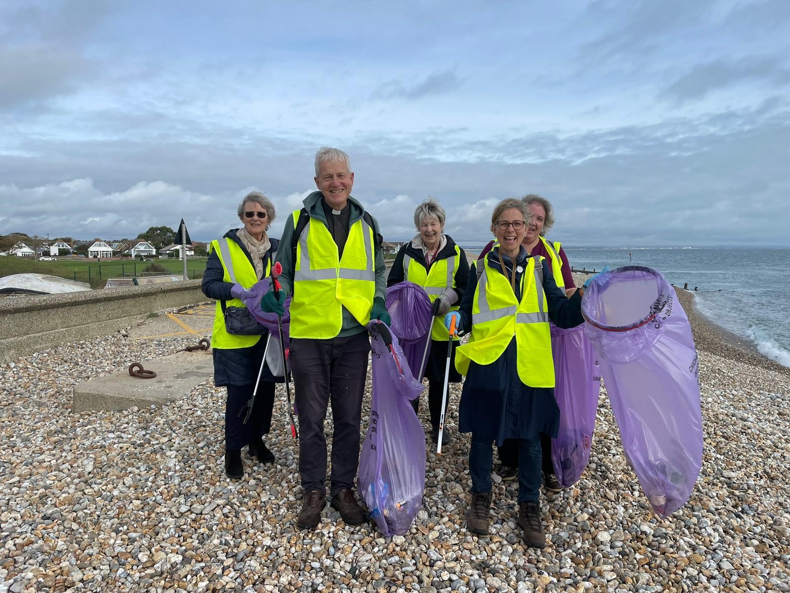 Cathedral staff taking part in a beach clean on selsey beach, holding bin bags